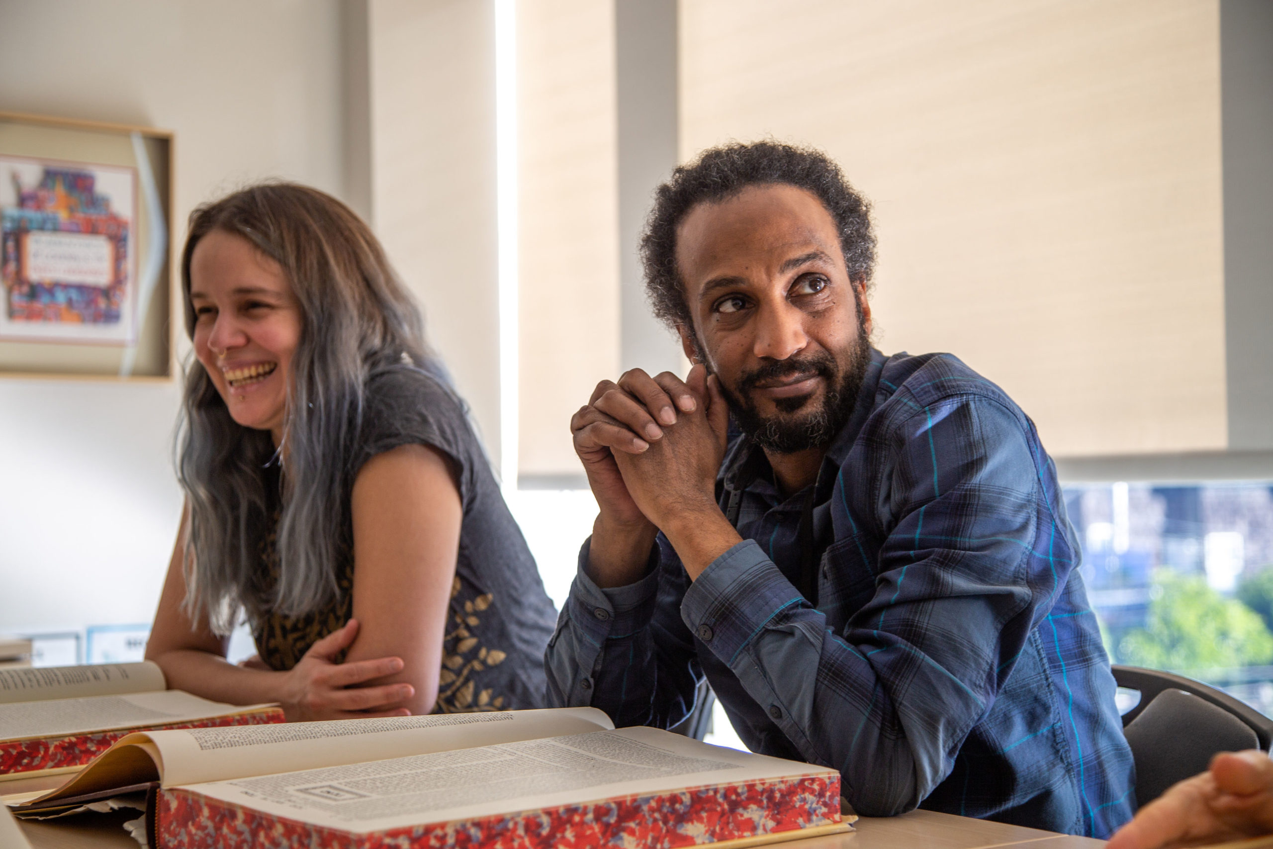 Man and woman sitting at table with book in front of them