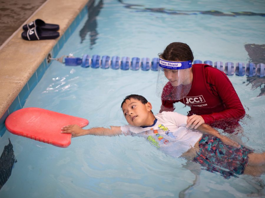 Boy in pool receiving swim lessons