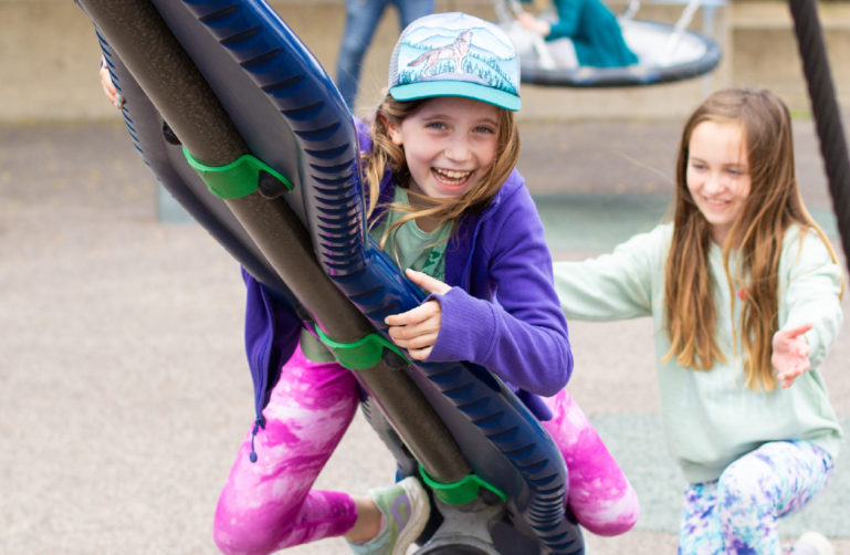 Kids smiling and playing on a playground.