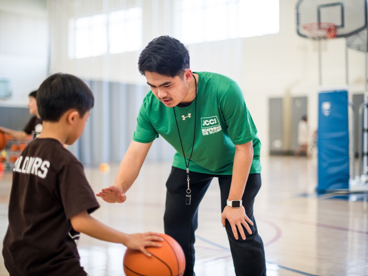 Basketball coach teaches a boy to dribble