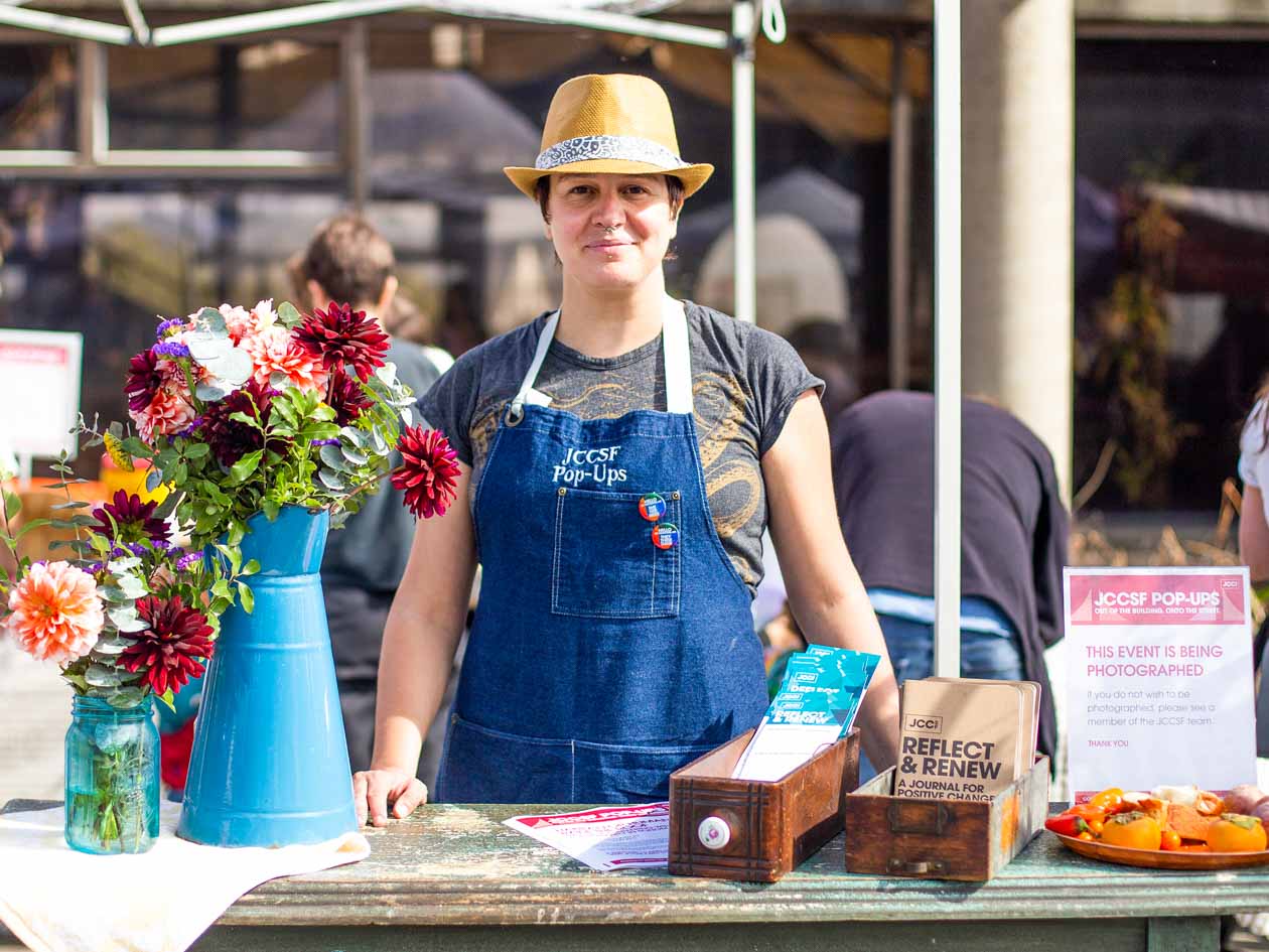 Woman stands at checkin table for JCCSF popup