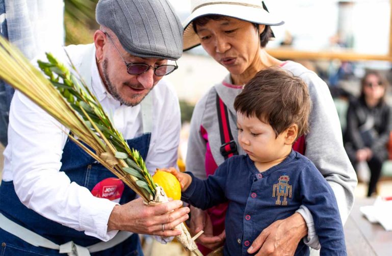 Merchant shows veggies to young boy