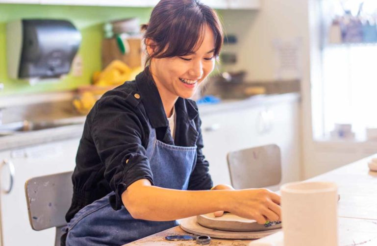 Smiling woman works on ceramics project