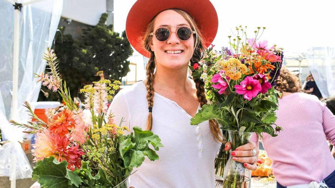 Woman in sunglasses holds two flower bouquets