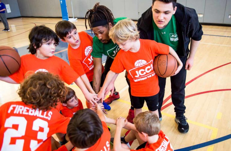 Youth basketball group circles up with hands in
