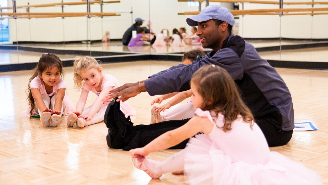 Kids and dance instructor stretching in the studio.