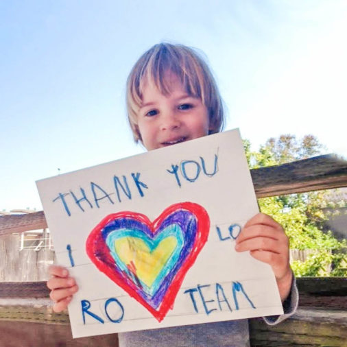Young boy holding up a thank you sign he made