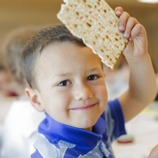 Young boy holding up a piece of matzo bread