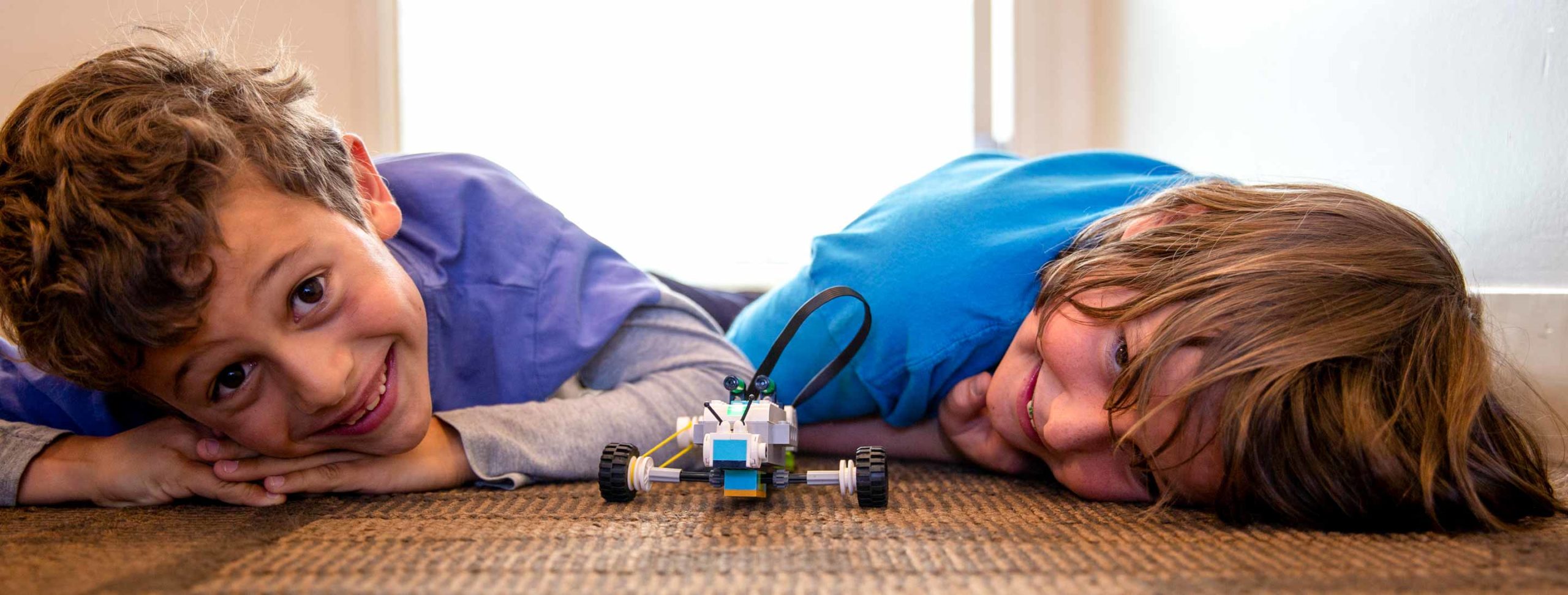 Smiling boys lie on floor with Legos