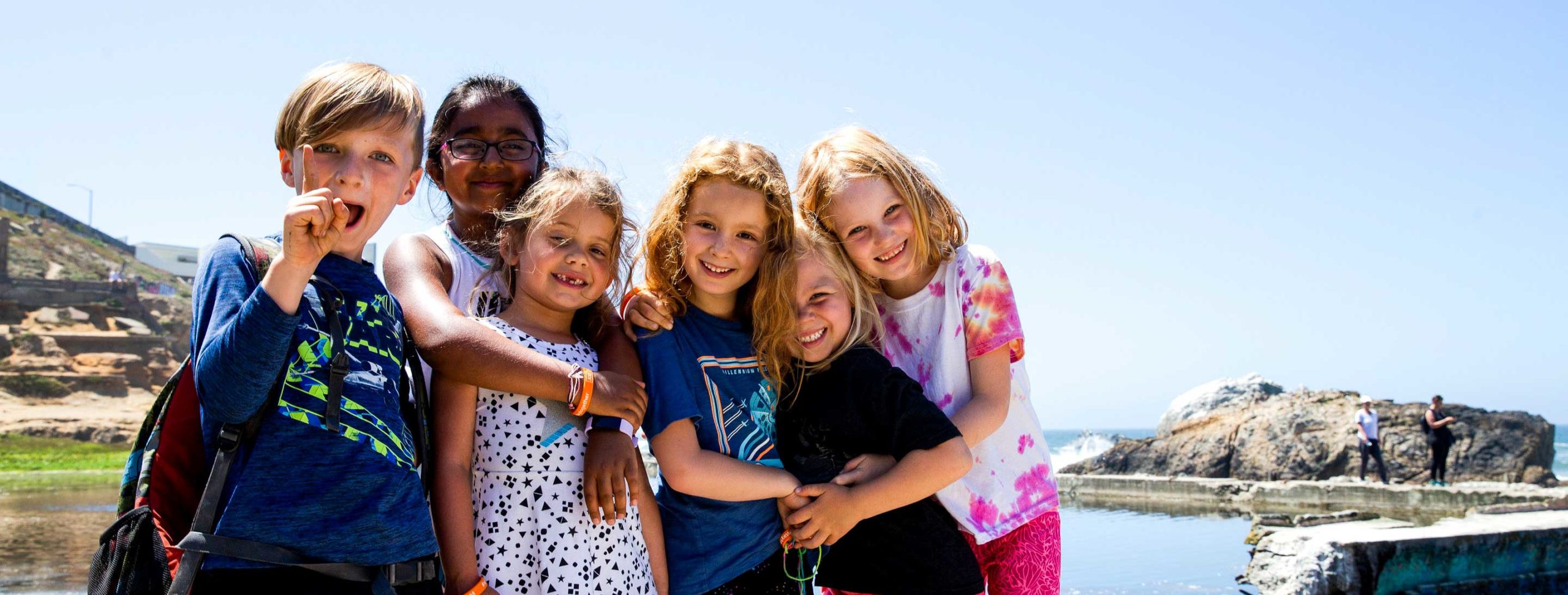 Group of kids hug each other while posing for camera