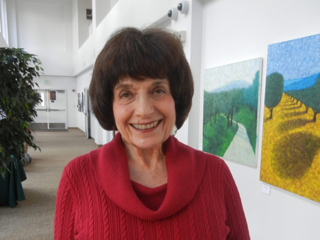 Photo of Betty Burr Smiling in front of paintings