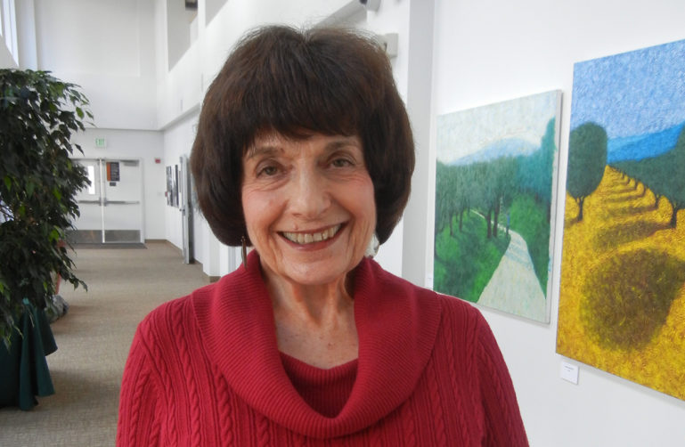 Photo of Betty Burr Smiling in front of paintings