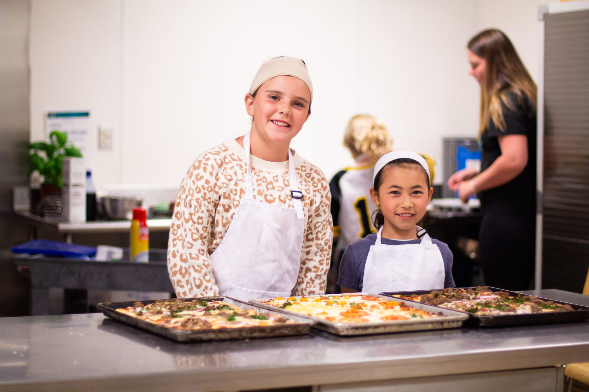 Campers smiling as they serve up pizza.