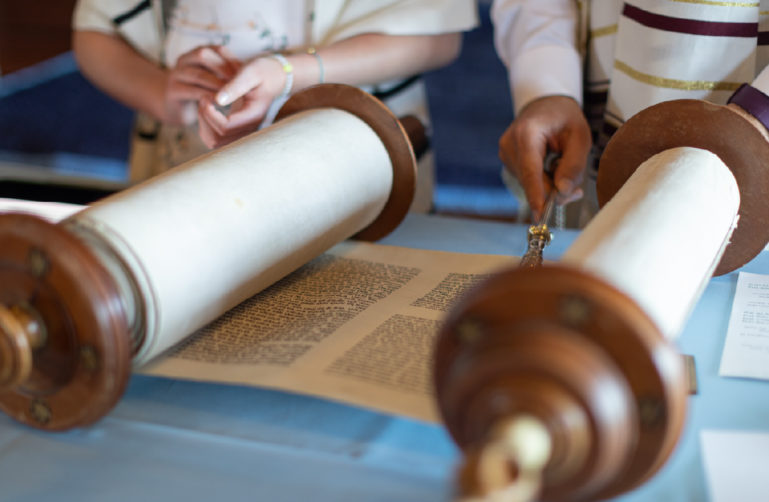 Image of the Torah unrolled on a table being read.