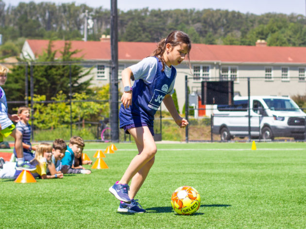 kids playing soccer on a sunny field