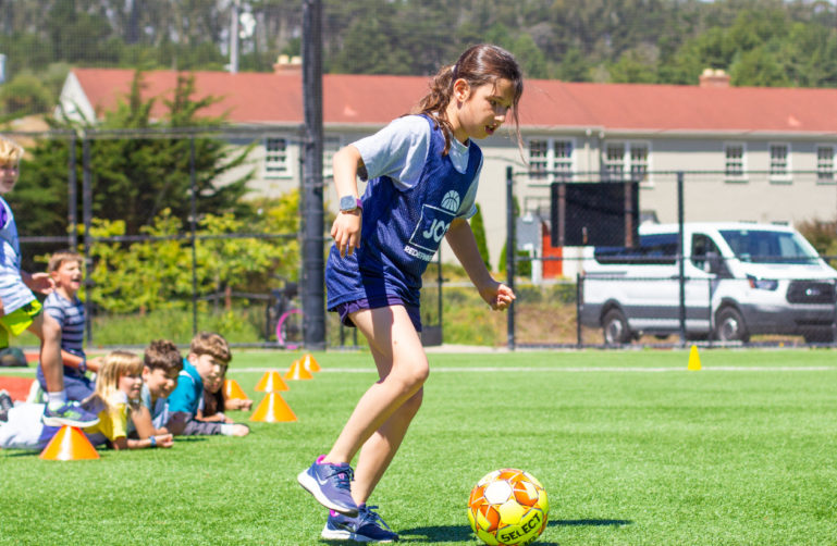 kids playing soccer on a sunny field