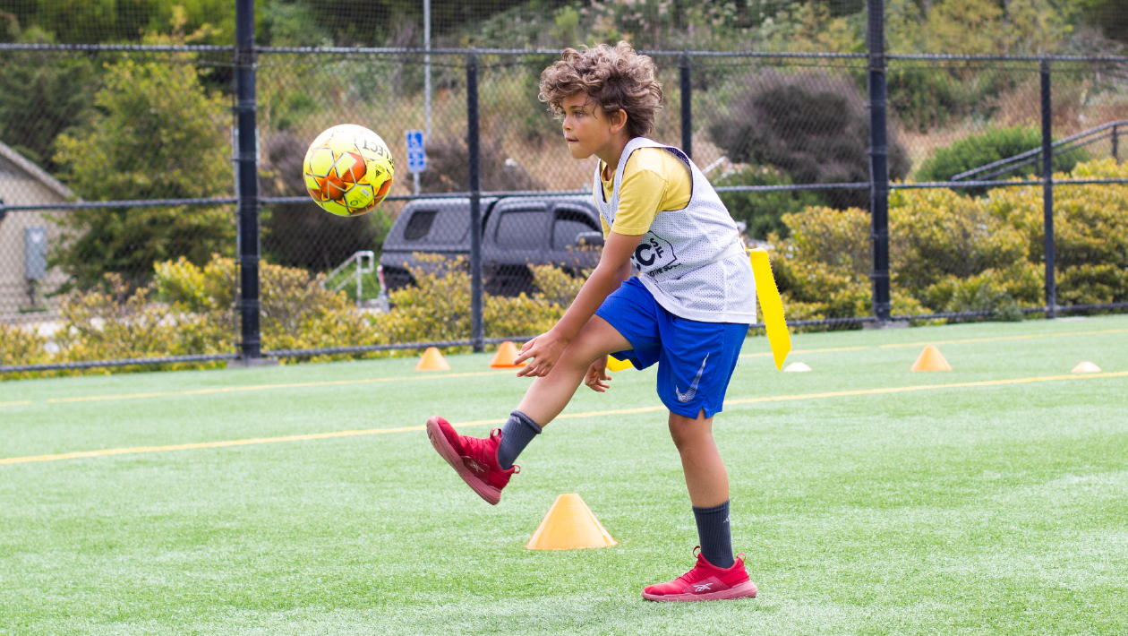 kid kicking a soccer ball on a field