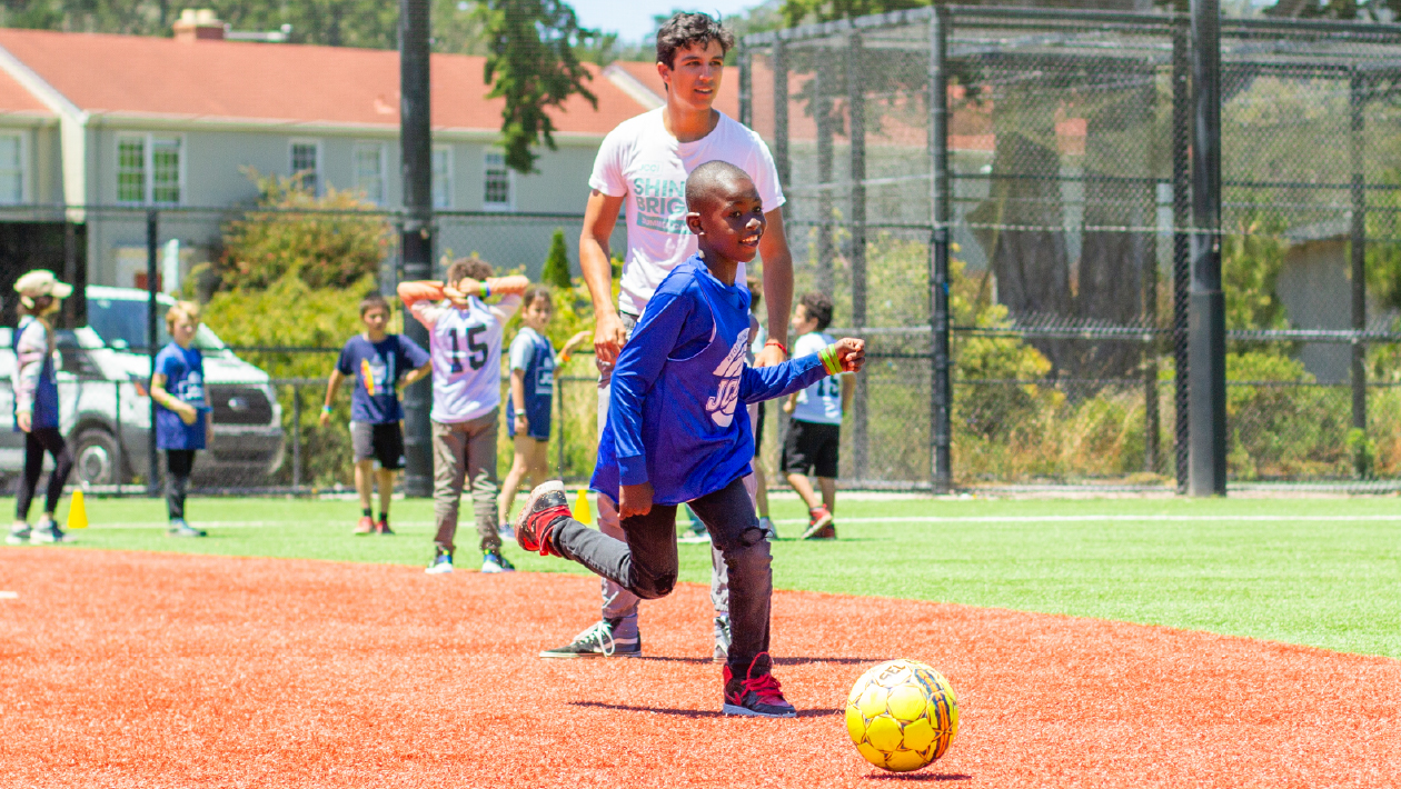 kids and coach playing soccer on a sunny field