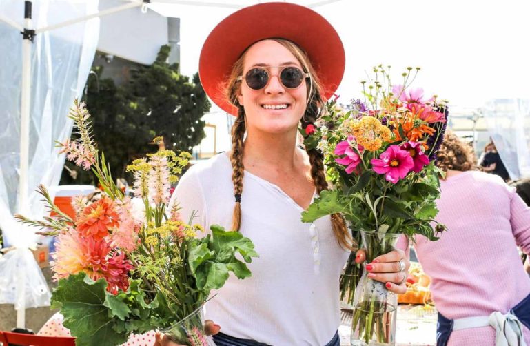 Woman in sunglasses holds two flower bouquets