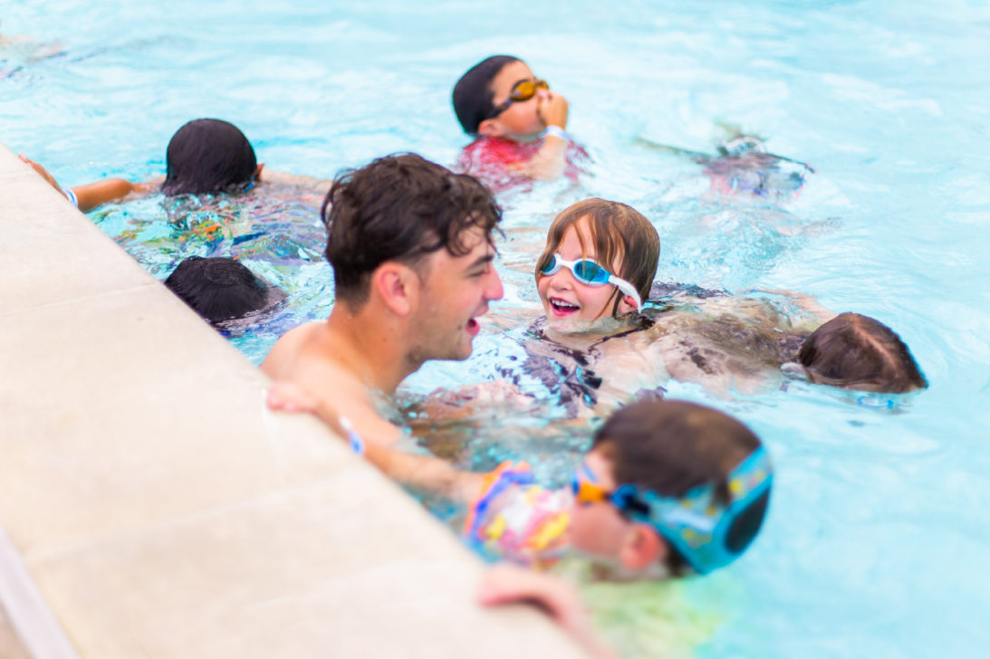 Summer camp counselor playing with kids in the pool.