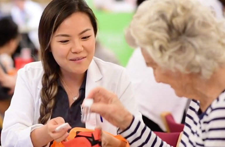 Picture of a nurse holding medicine bottles while talking to a woman.