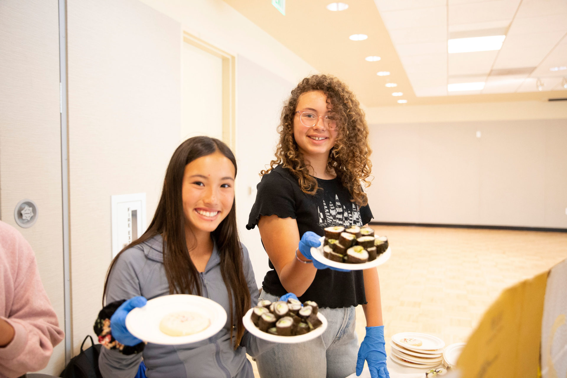 Campers smiling and holding plates of food.