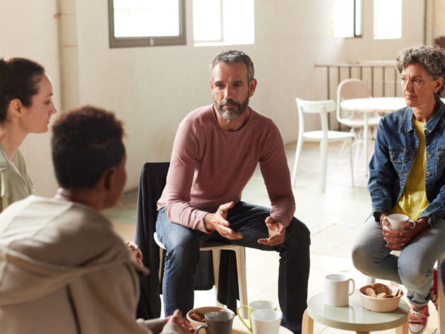 Group of adults sitting in a circle and talking.