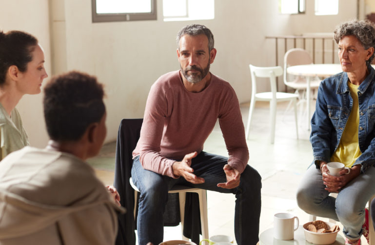 Group of adults sitting in a circle and talking.